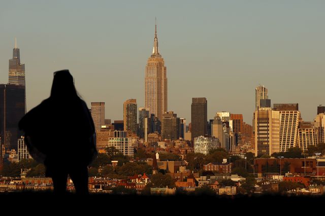 A woman looks out at the Empire State Building as the sun sets in New York City on Sept. 15, 2022, as seen from Jersey City